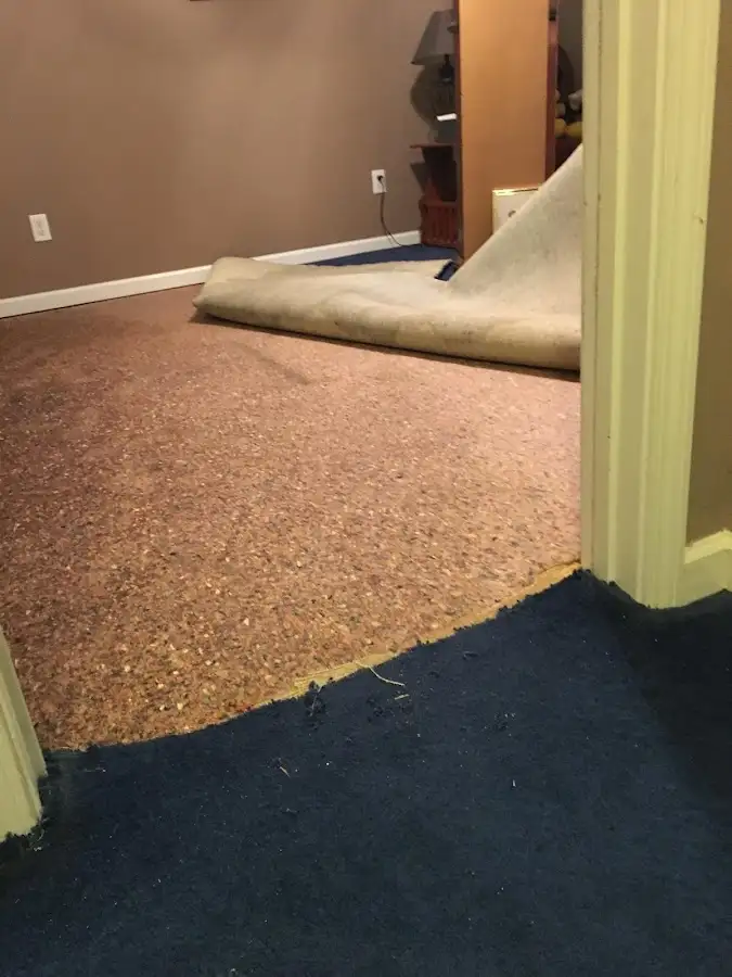Carpet pad removal revealing water damage during Water Mitigation Services in Huntington